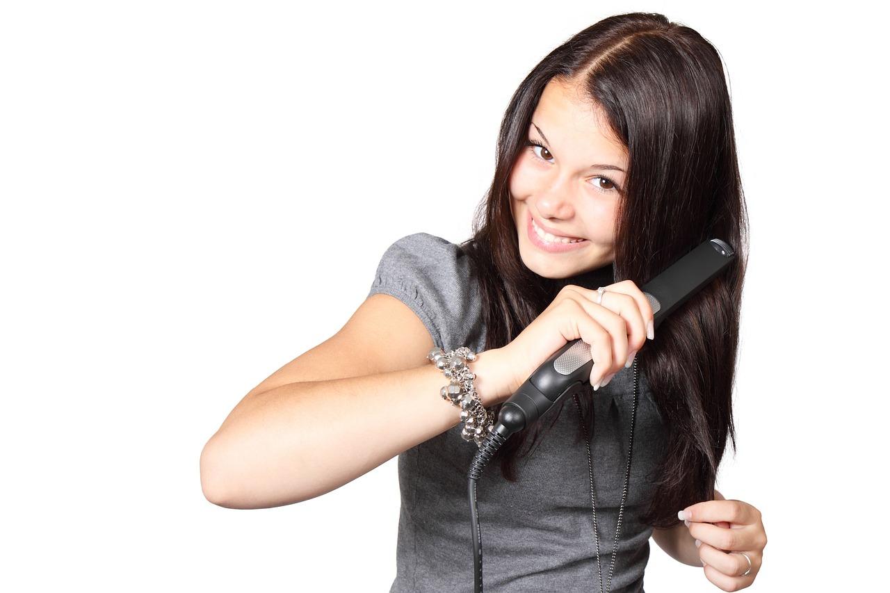 Girl straightens hair with a curling iron