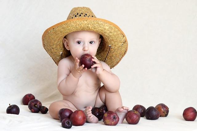 Photo of a baby in a hat and with plums